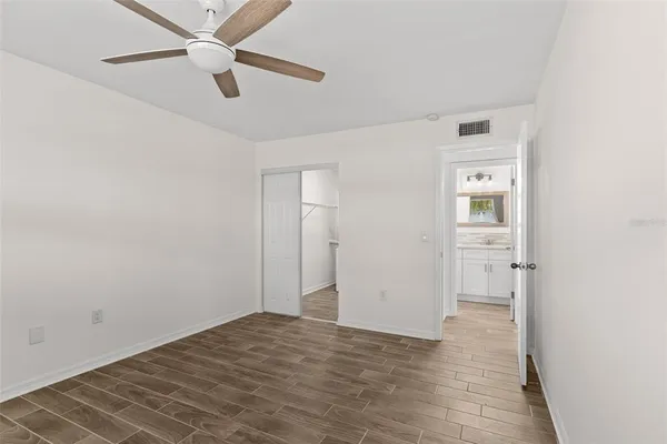 an empty room with closet and a ceiling fan