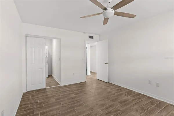 an empty room with wooden floor ceiling fan and closet area