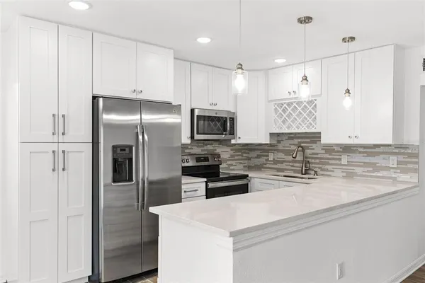 a kitchen with stainless steel appliances granite countertop a refrigerator a stove and a sink