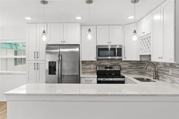 a kitchen with stainless steel appliances a refrigerator a stove and white cabinets
