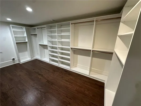 a view of an empty room with wooden floor and closet