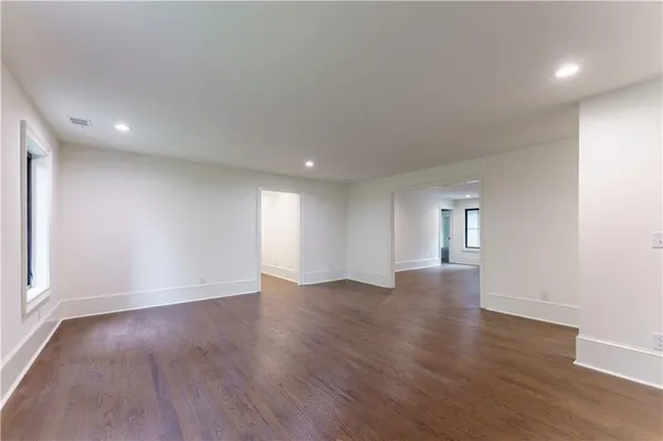 a view of an empty room with wooden floor and window