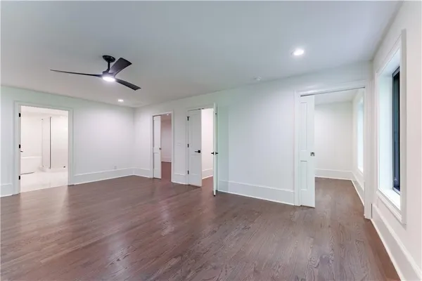 a view of an empty room with wooden floor and a ceiling fan