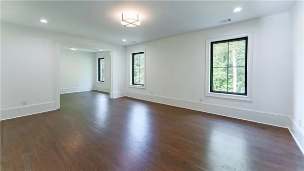 an empty room with wooden floor and windows