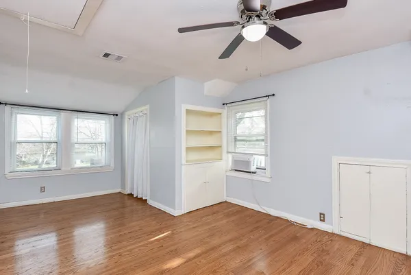 a view of an empty room with window and wooden floor