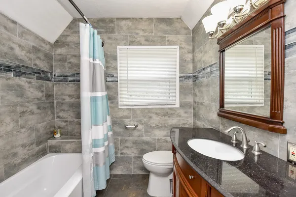 a bathroom with a granite countertop sink a toilet a mirror and shower