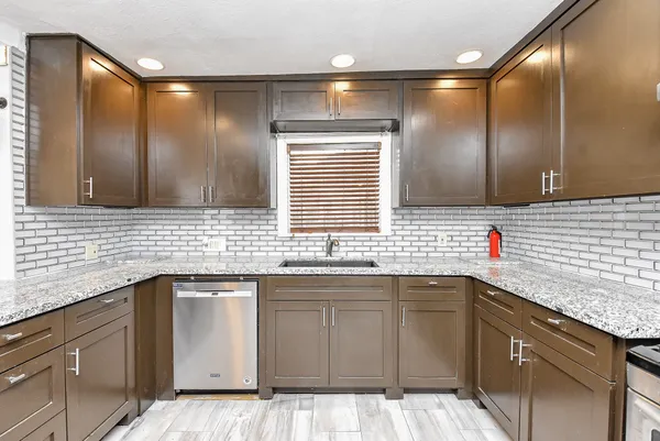 a kitchen with a sink dishwasher a stove and cabinets