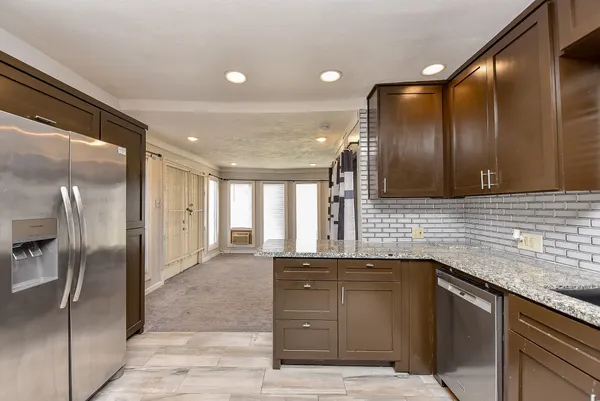 a kitchen with granite countertop a refrigerator and cabinets