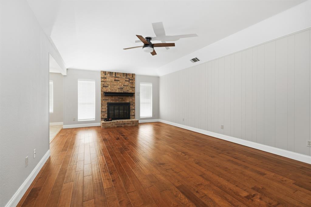 7205 Windcrest Court East North Richland Hills, TX 76182 - Photo 11 of 35 an empty room with wooden floor fireplace and windows