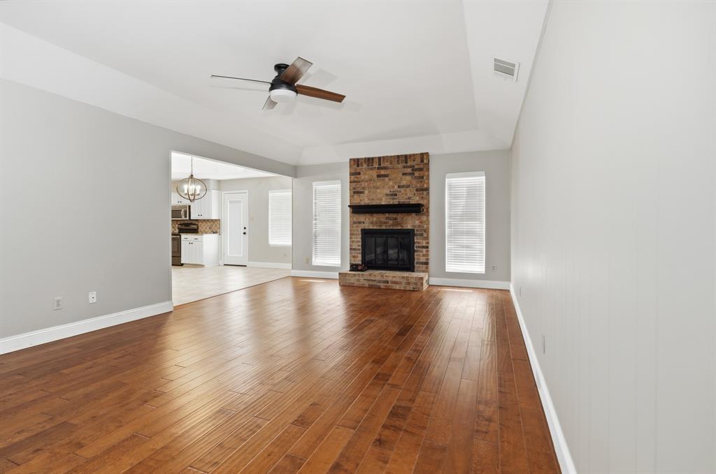7205 Windcrest Court East North Richland Hills, TX 76182 - Photo 12 of 35 an empty room with wooden floor fireplace and windows