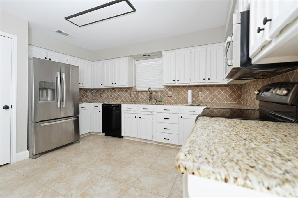7205 Windcrest Court East North Richland Hills, TX 76182 - Photo 14 of 35 a kitchen with white cabinets and stainless steel appliances