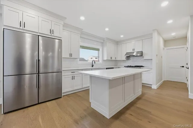 a kitchen with white cabinets stainless steel appliances and a refrigerator