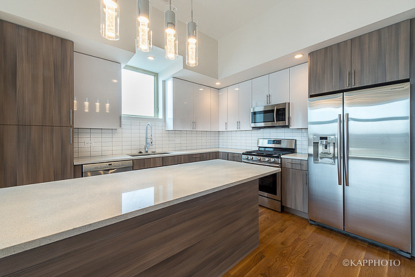2835 West Division Street, Unit 1W Chicago, IL 60622 - Photo 11 of 39 a kitchen with granite countertop a refrigerator a sink dishwasher a stove and white cabinets with wooden floor
