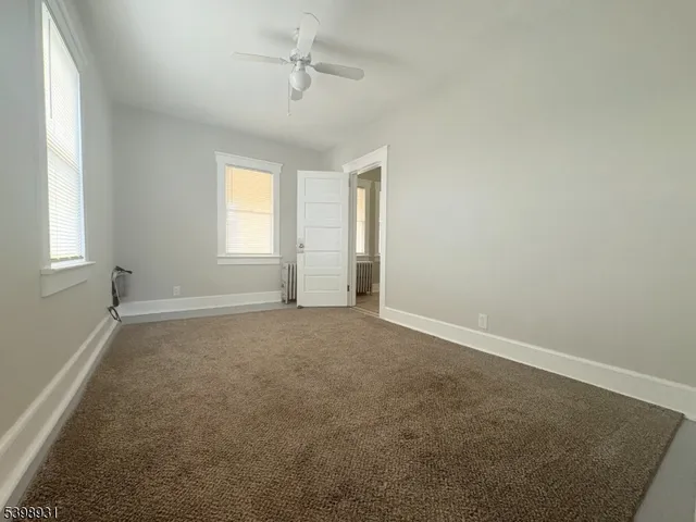 an empty room with windows and fan