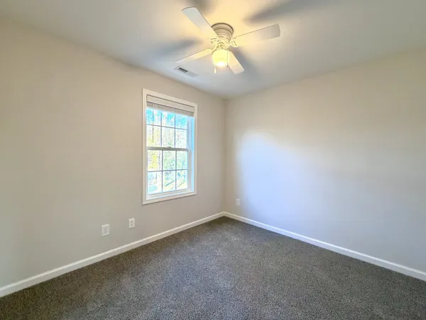 an empty room with a window and a fan