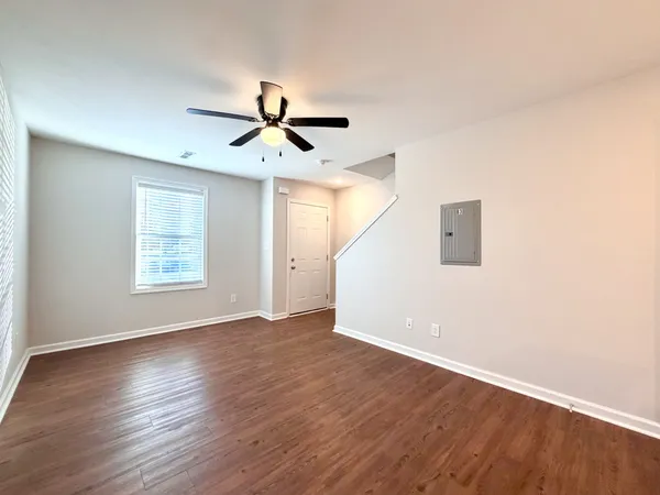 a view of empty room with wooden floor and fan
