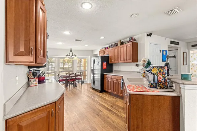 a kitchen with stainless steel appliances granite countertop a refrigerator a oven a sink dishwasher and white cabinets with wooden floor