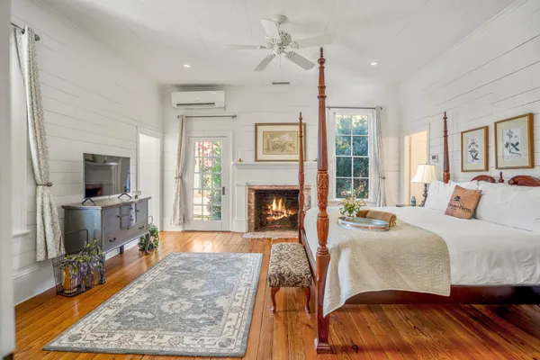 a spacious bedroom with a bed a fireplace and a flat tv screen