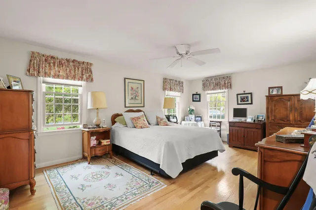 a bedroom with a bed large window desk and chair