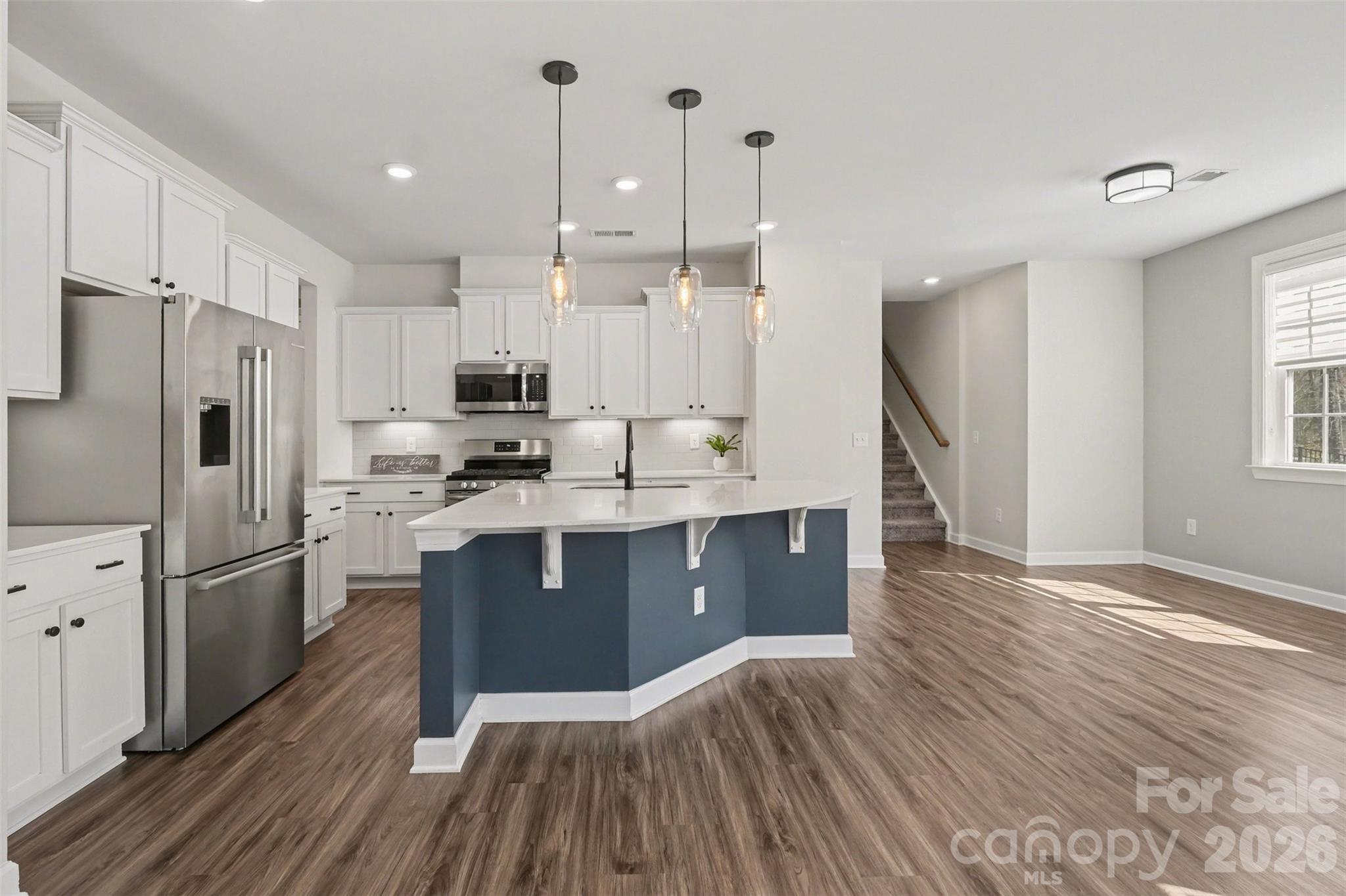 14510 Grundys Way Davidson, NC 28036 - Photo 12 of 43 a kitchen with kitchen island granite countertop a refrigerator oven a sink dishwasher and white cabinets with wooden floor
