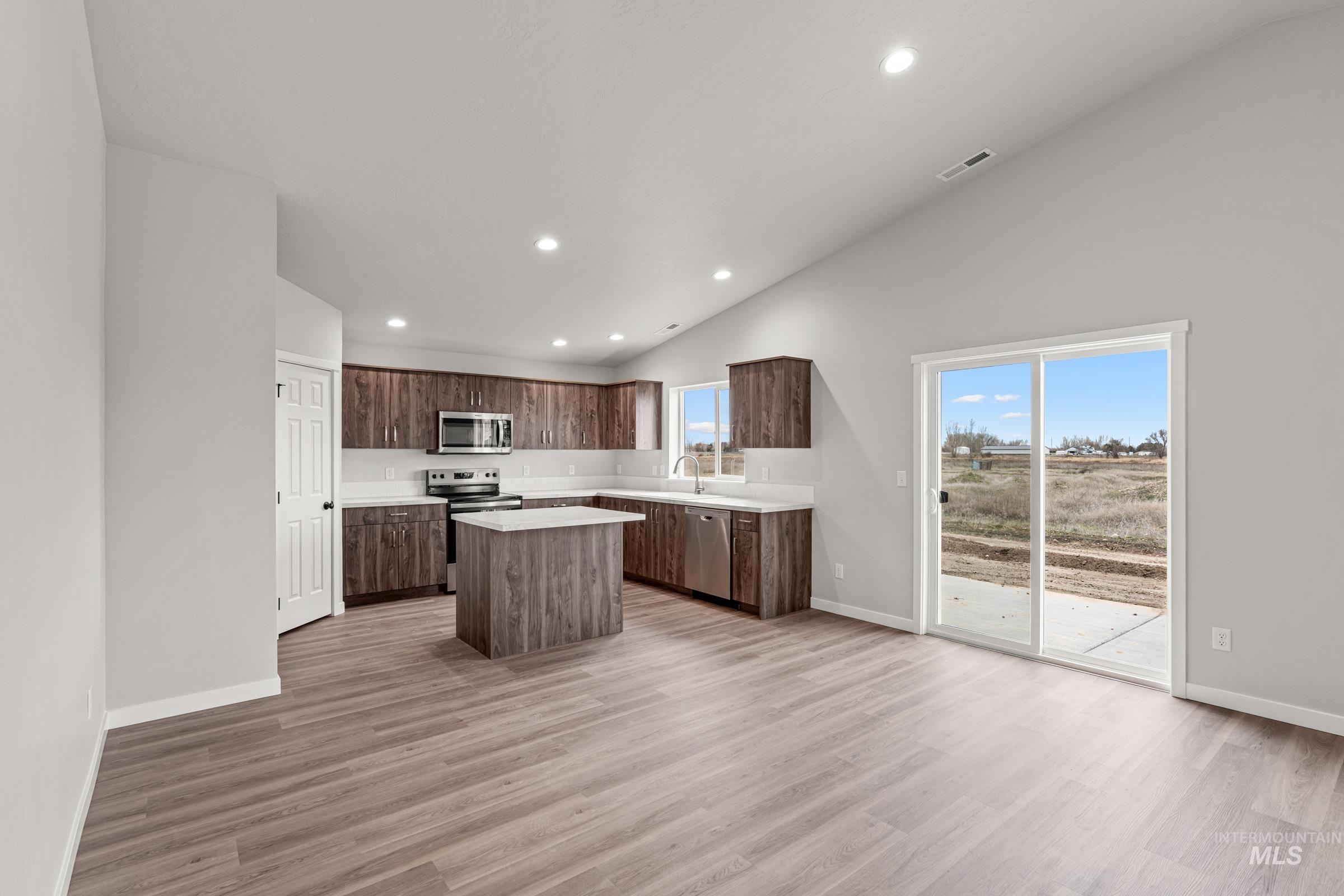 1449 Covington Street Middleton, ID 83644 - Photo 3 of 21 Kitchen with a kitchen island, stainless steel appliances, lofted ceiling, dark wood finish cabinets, and recessed lighting