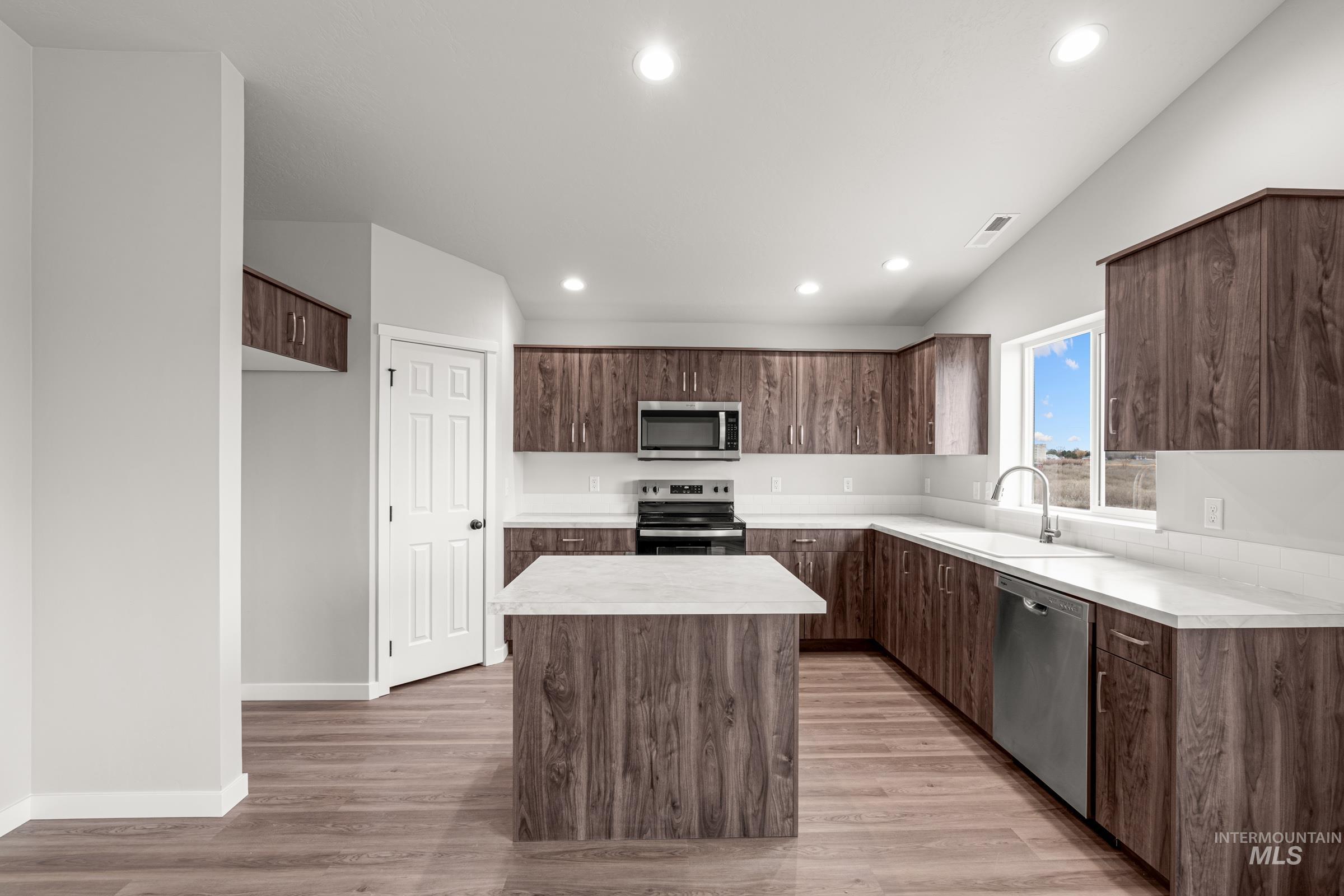 1449 Covington Street Middleton, ID 83644 - Photo 4 of 21 Kitchen featuring stainless steel appliances, light countertops, light wood-style flooring, a center island, and dark wood finish cabinets