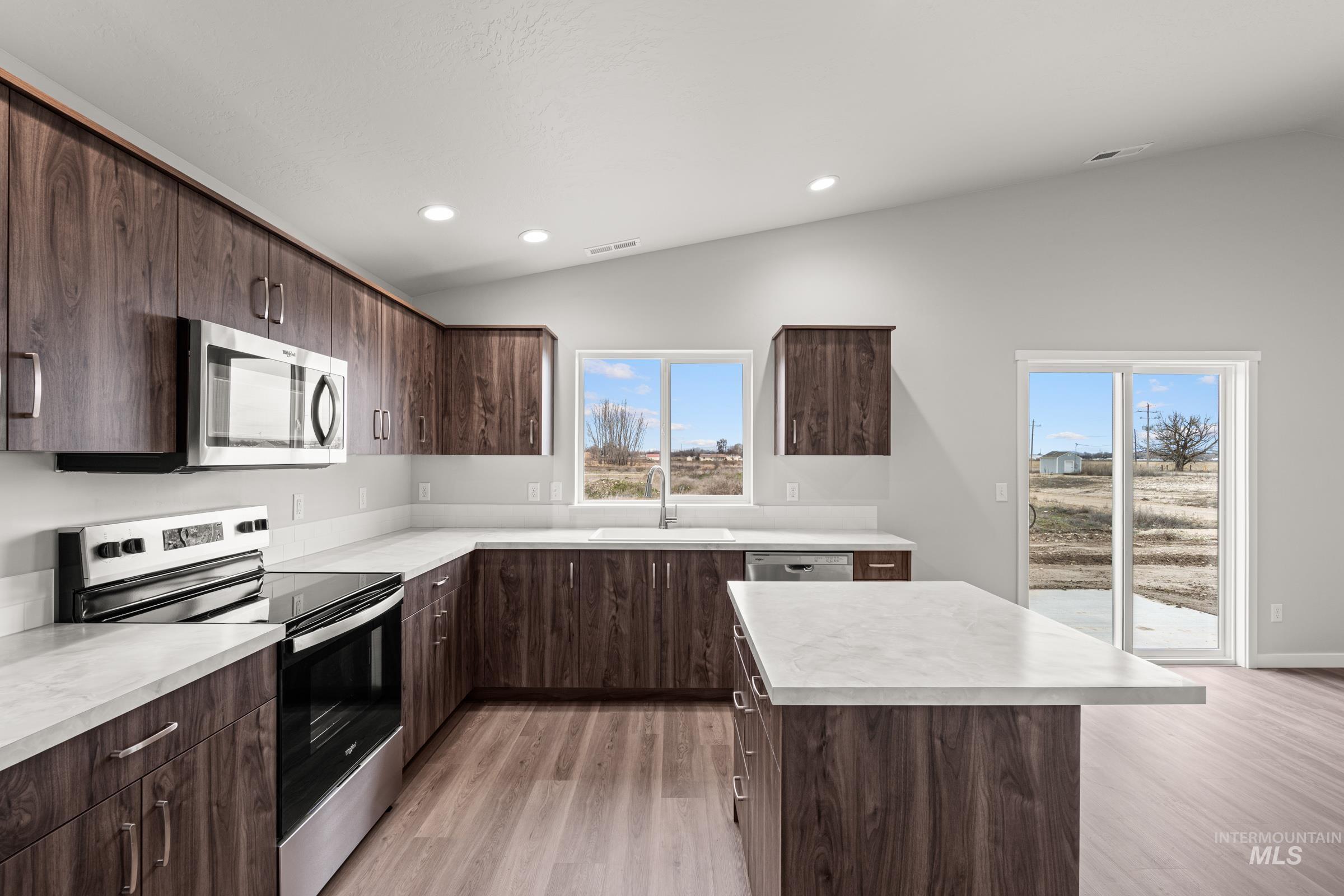 1449 Covington Street Middleton, ID 83644 - Photo 6 of 21 Kitchen with stainless steel appliances, dark wood finish cabinetry, lofted ceiling, light countertops, and light wood-style flooring