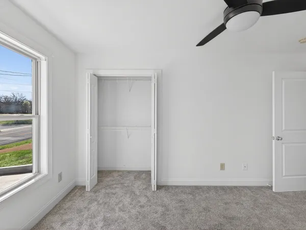 en empty room with windows and ceiling fan