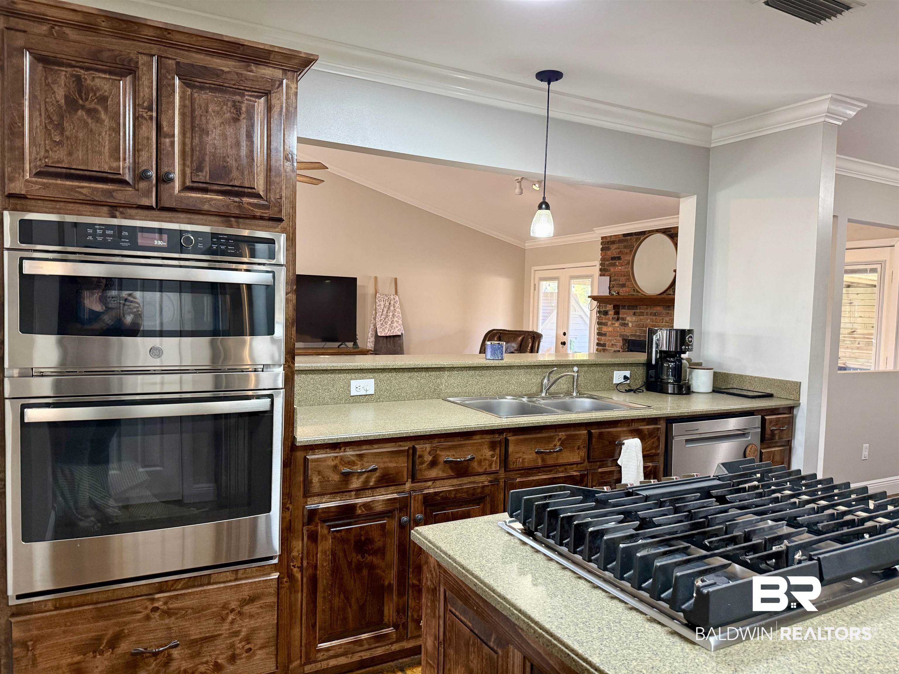 5646 Foshee Road Brewton, AL 36426 - Photo 9 of 37 Kitchen with stainless steel appliances, dark wood finish cabinets, hanging light fixtures, ornamental molding, and light stone counters