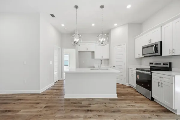 a kitchen with kitchen island white cabinets stainless steel appliances and a chandelier
