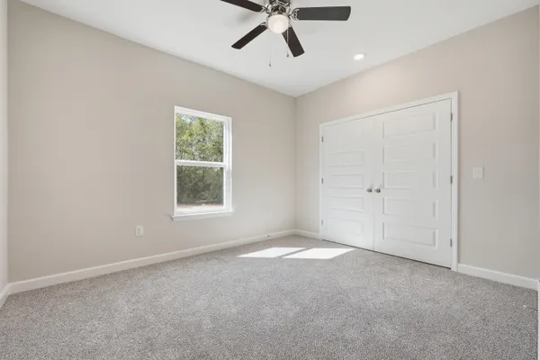 an empty room with ceiling fan and window