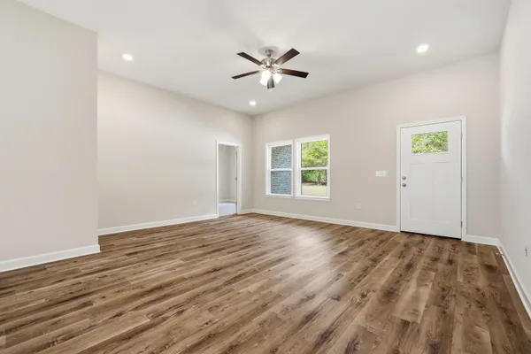 a view of kitchen and empty room with wooden floor