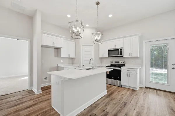 a large kitchen with granite countertop a stove top oven a sink a counter space and cabinets