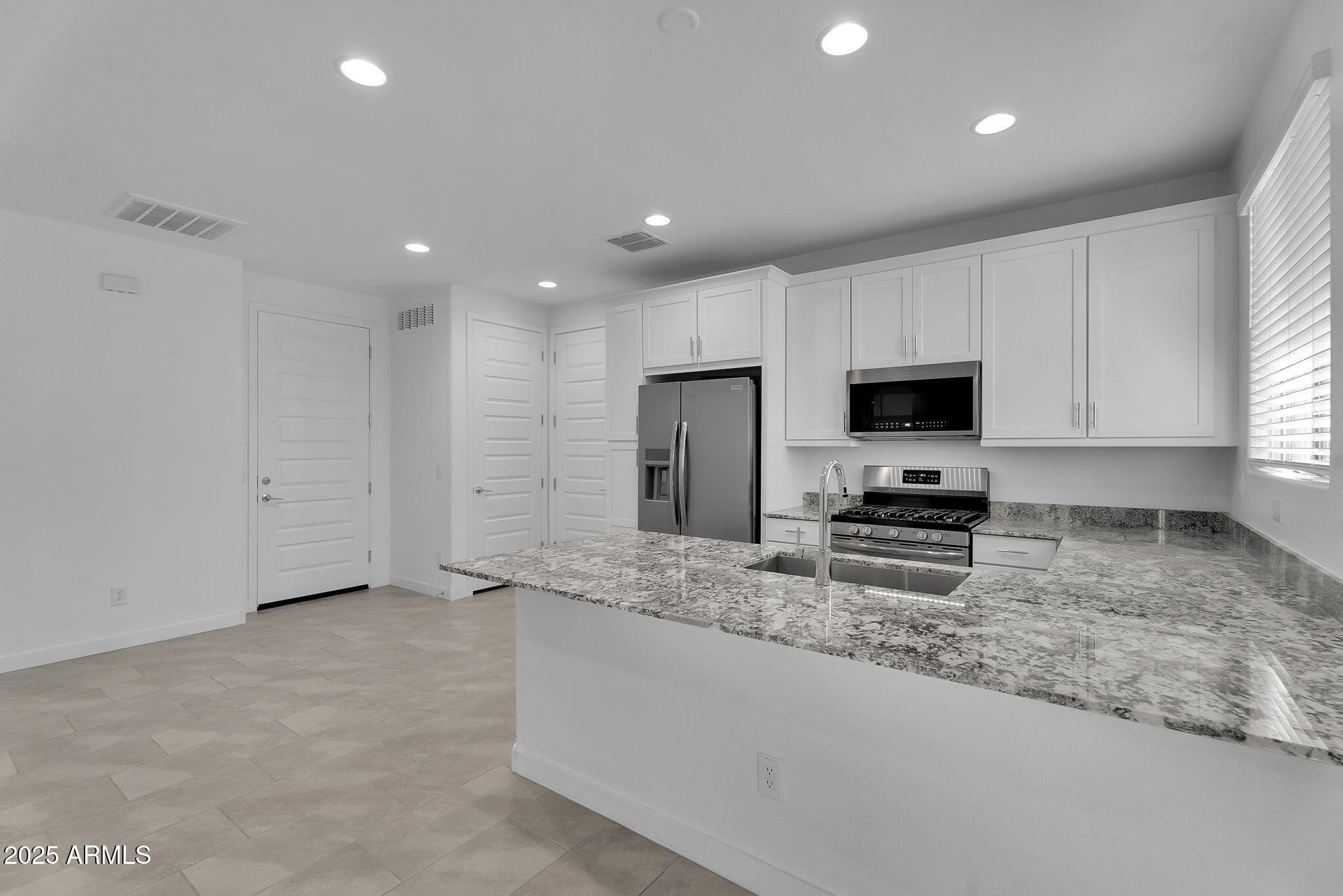 19948 West Flower Street Buckeye, AZ 85396 - Photo 20 of 58 a kitchen with stainless steel appliances granite countertop a sink a stove a microwave a refrigerator and white cabinets