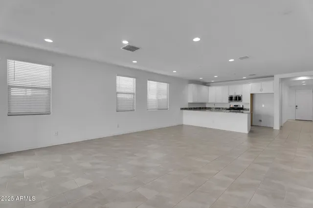 a view of an empty room with kitchen view and window