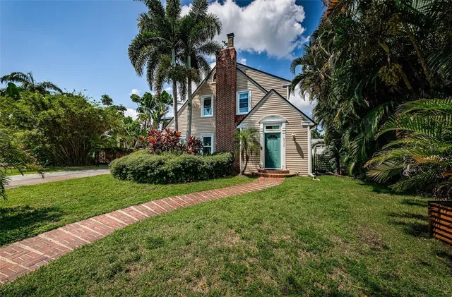 a view of a house with a yard and palm trees
