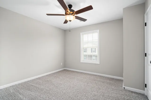 an empty room with a window and a fan