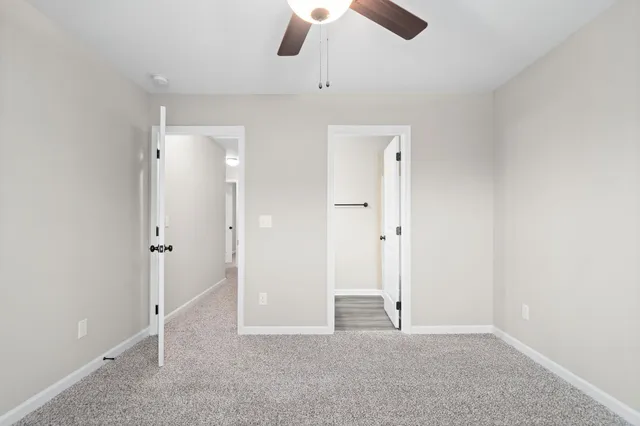 an empty room with ceiling fan and window