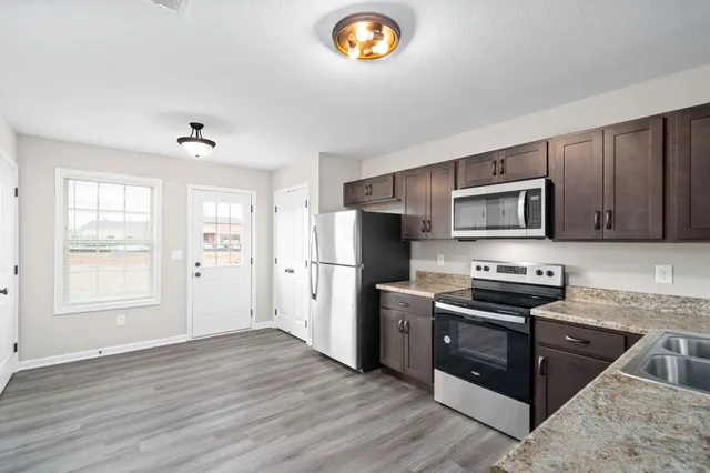 a kitchen with granite countertop a refrigerator stove and microwave