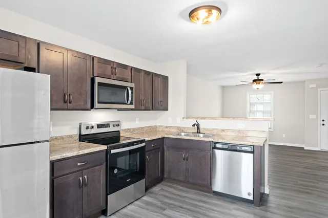 a kitchen with granite countertop a sink stainless steel appliances and cabinets