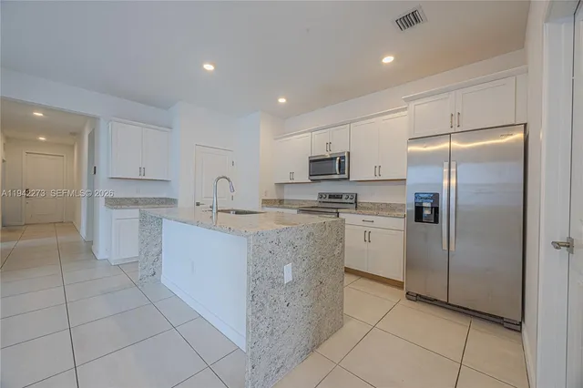 a view of a kitchen with refrigerator and white cabinets