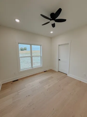 an empty room with ceiling fan and window