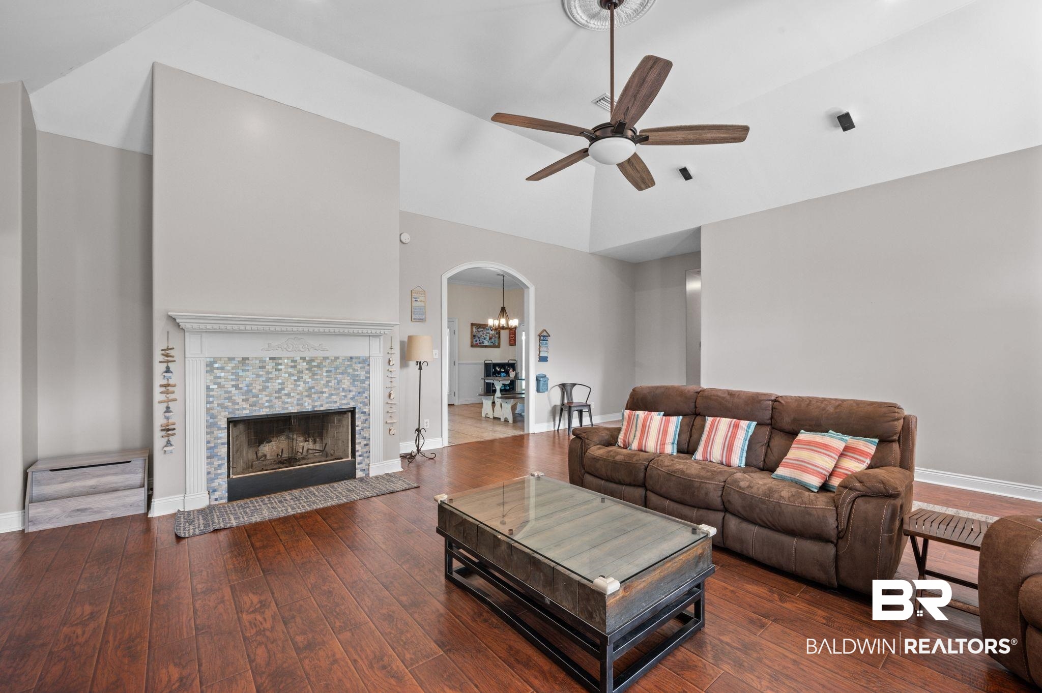 48513 Phillipsville Road Bay Minette, AL 36507 - Photo 11 of 50 Living room featuring arched walkways, a ceiling fan, hardwood / wood-style floors, a high ceiling, and a tiled fireplace