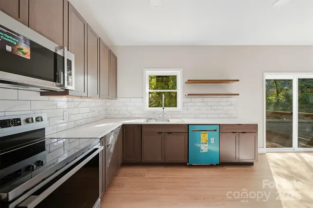 a kitchen with stainless steel appliances granite countertop a stove a sink and a microwave