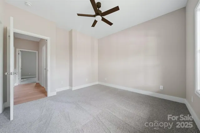 an empty room with closet and a chandelier fan