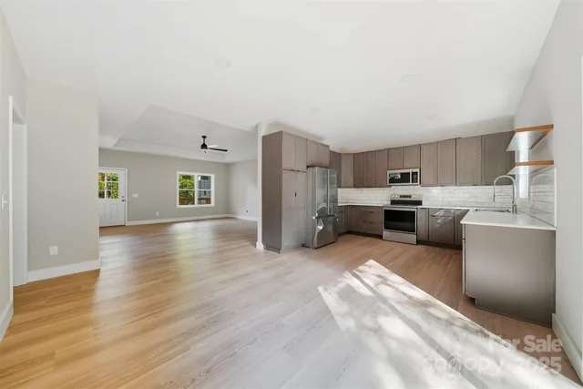 a view of a kitchen with a sink stove cabinets and empty room