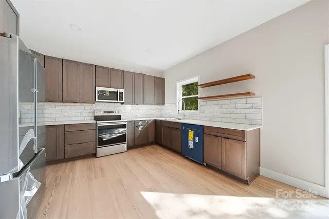 a kitchen with granite countertop a refrigerator cabinets stainless steel appliances and a counter space