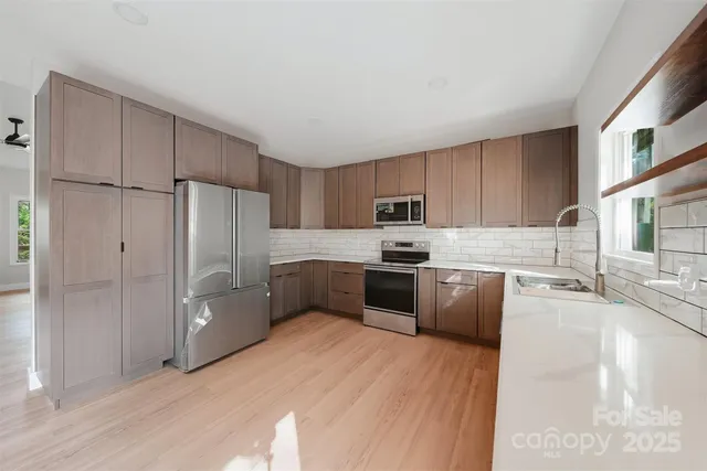 a kitchen with stainless steel appliances granite countertop a refrigerator a sink dishwasher a stove and a refrigerator with wooden floor