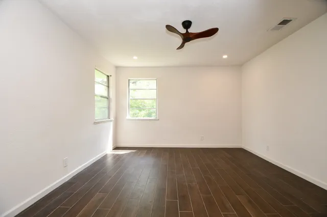 an empty room with wooden floor and windows
