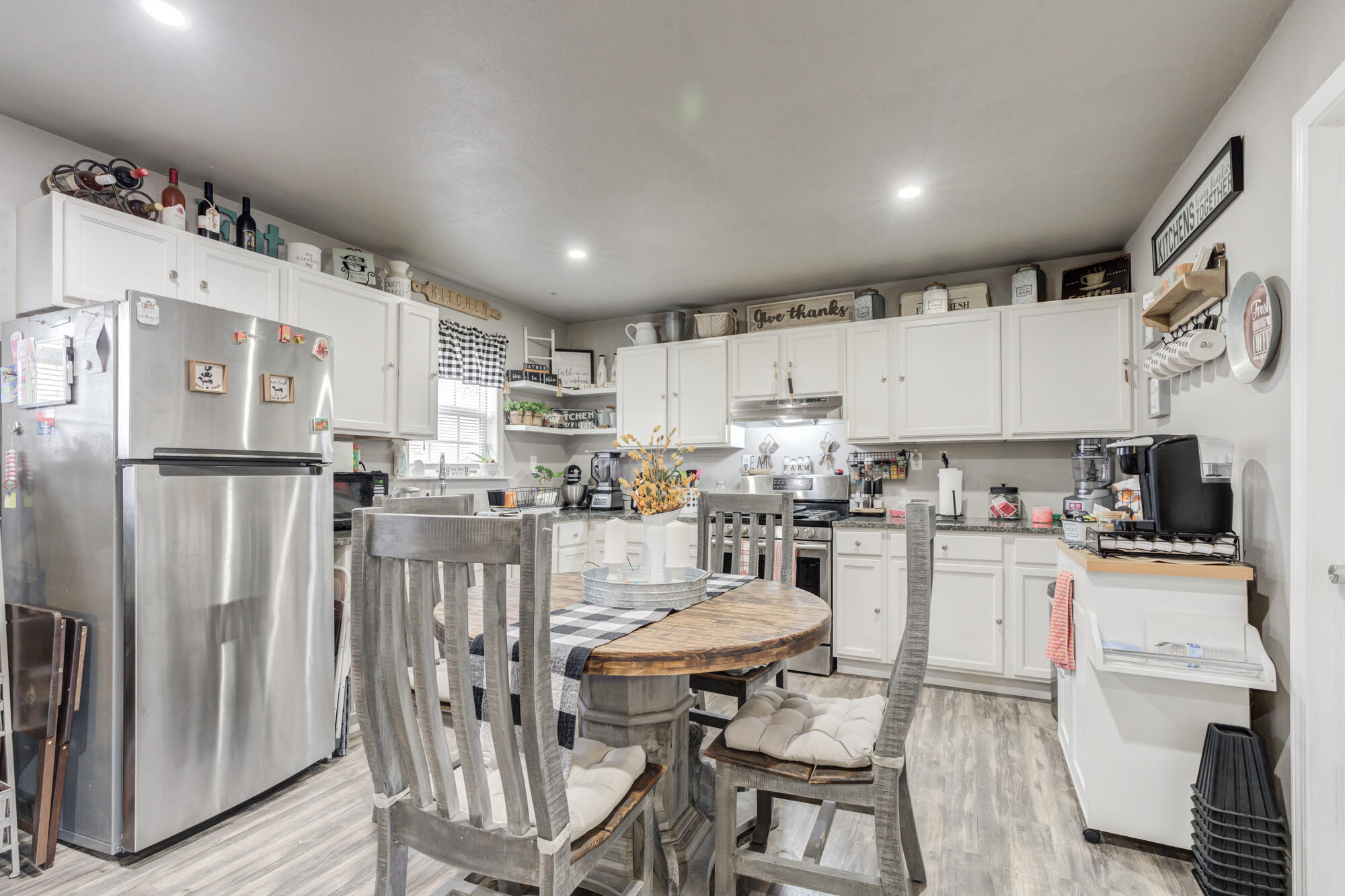 1515 36th Street Lubbock, TX 79412 - Photo 8 of 23 a kitchen with stainless steel appliances granite countertop a refrigerator a stove a sink dishwasher and white cabinets with wooden floor